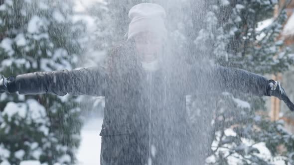 Medium Shot Portrait of Excited Girl Tossing Snow Spinning in Slow Motion Smiling Looking at Camera