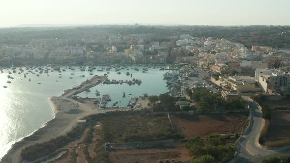 Beach Town with Bay Full of Boats on Malta Island at Sunset, Aerial Drone Perspective