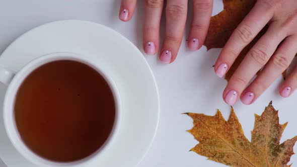 Woman Showing Hands with Beautiful Nude Manicure Holding Autumn Leaves