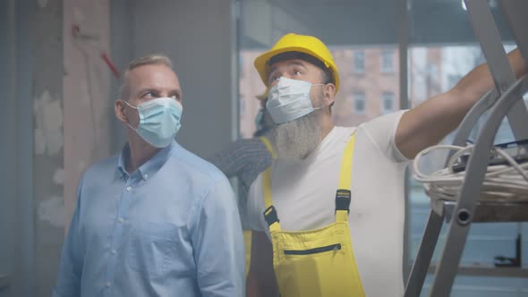 Male Customer and Foreman in Protective Mask Examining Renovation Process