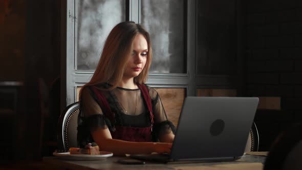 Happy Young Woman Drinking Coffee and Using Tablet Computer in Cafe