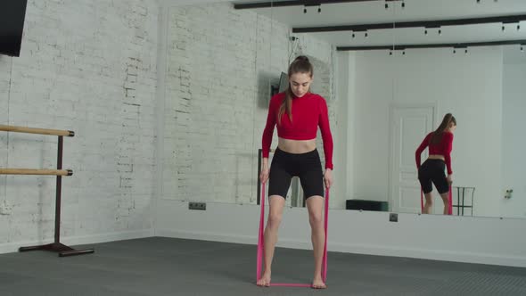 Sporty Woman Exercising with Resistance Band at Gym