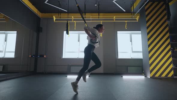 Sporty Woman Doing TRX Exercises in the Gym