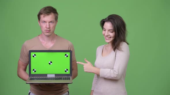 Young Couple Showing Laptop and Pointing Finger Together