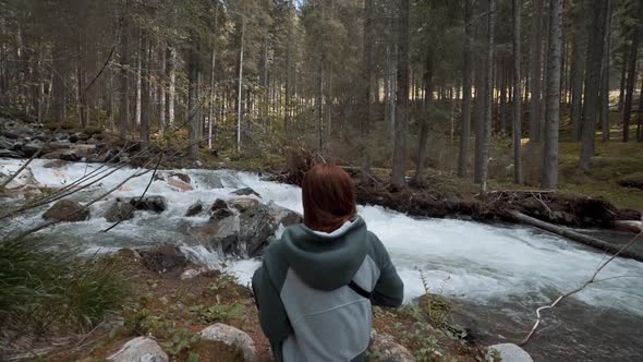 Happy Young Redhaired Woman Photographs a Mountain Forest and a River in the Dolomites Mountains