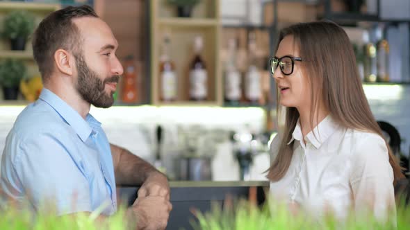 European Man and Woman Laughing and Having Informal Meeting Sitting on Bar