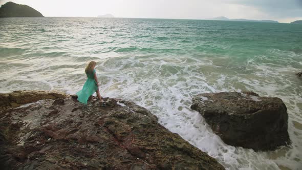 Woman Walks on Rock of Sea Reef Stone Stormy Cloudy Ocean