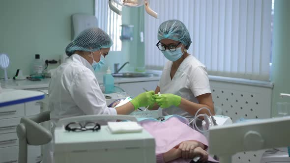 Expert Caucasian Dental Assistant Passing Sterile Instrument to Dentist in Slow Motion in Hospital
