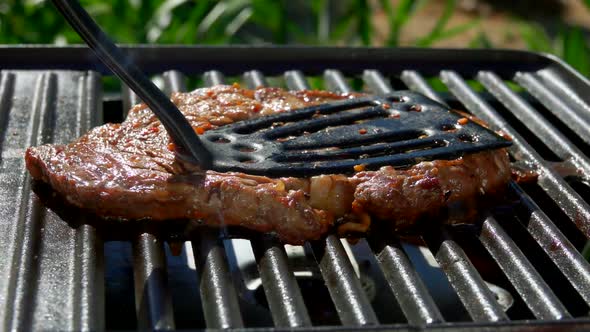 Steak Is Pressed By Kitchen Spatula To the Grill