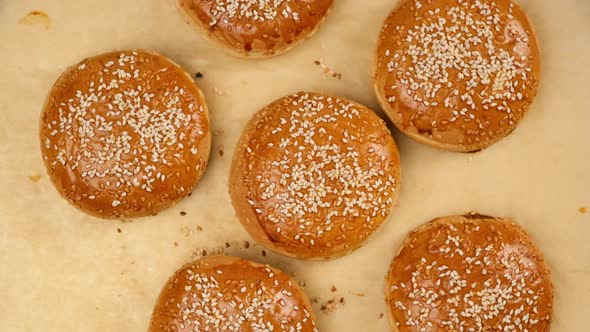 baked sesame buns on brown parchment paper, ingredient for a hamburger