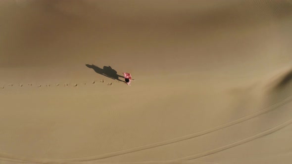 Aerial view of attractive woman walking at a desert landscape, U.A.E.