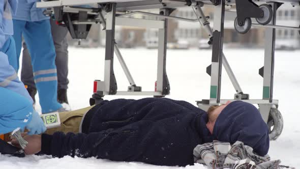 Paramedics Preparing Stretcher for Patient Lying on Snow