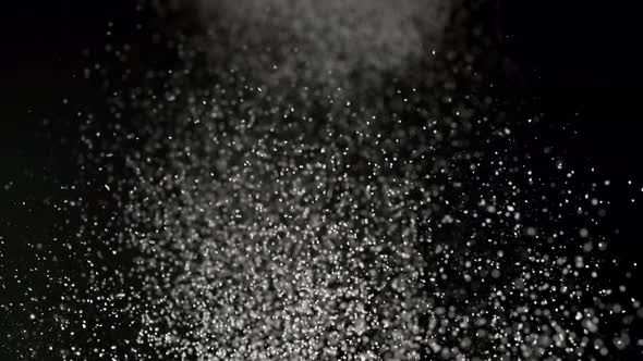 Dusting flour on black background. Slow Motion.