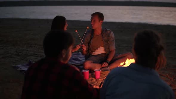 Young Couple on Perspective are Feeding Each Other with Marshmallows From the Sticks