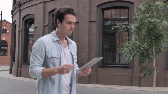 Man Walking on Street Dancing and Listening Music on Tablet