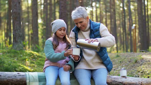 Grandma with Granddaughter Drinking Tea in Forest
