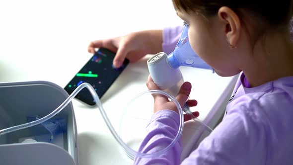 Little Girl is Sick Makes Inhalation with Nebulizer and Play Games on Martphone