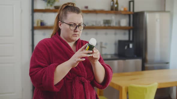 Overweigh Woman Reading Instructions on Bottle of Herbal Extract Natural Diet Pills