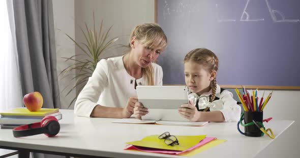 Portrait of Caucasian Female Private Tutor Teaching Cute Child with Pigtails at Home