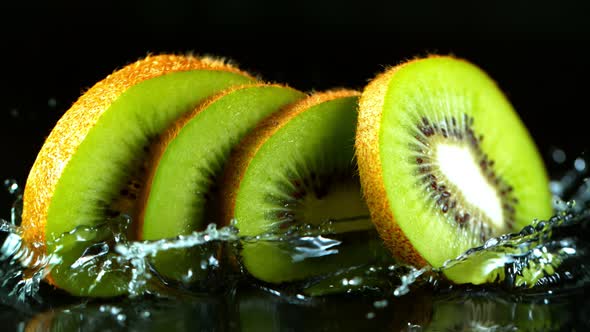 Super Slow Motion Shot of Falling And Splashing Kiwi Slice Isolated on Black Background at 1000Fps.