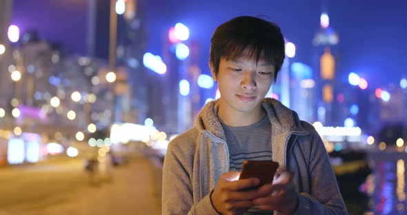 Asian Man using mobile phone in city at night
