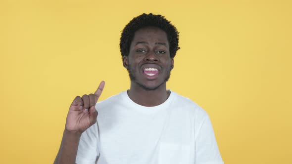 African Man Waving Finger To Refuse, Yellow Background