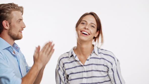 Young Caucasian Couple Gives High Five with Two Hands to Each Other and Smiling on White Background