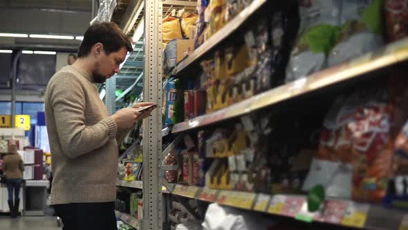 The Darkhaired Man Chooses Food for His Dog or Cat in the Mall