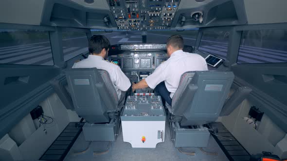 Two Pilots Check Equipment in a Cockpit