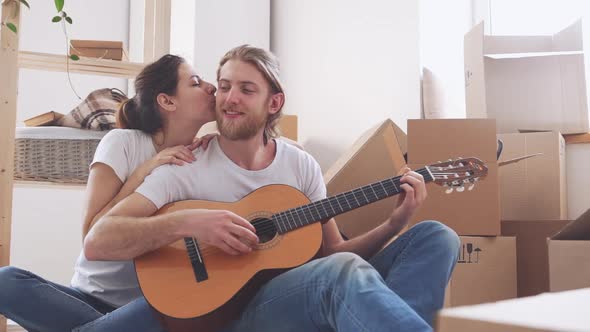 Happy Caucasian Pair Playing on Guitar in New Apartment in Slowmotion