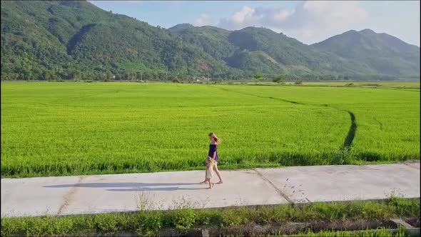 Aerial View of Woman Walking with Girl Along Road By Rice Field