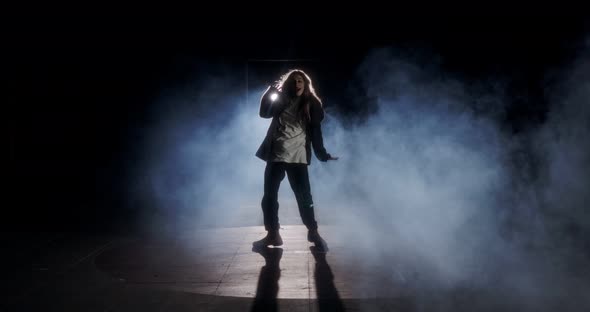 Young female dancer performing wild hip hop dance with strobe light and smoke background