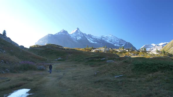 One person with backpack hiking in high altitude mountain environment, dramatic alpine landscape