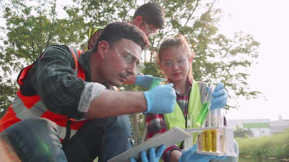 leader and assistants check contaminants in factory wastewater in a test tube