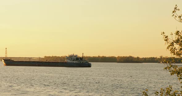 Big Industrial ship standing near industrial city crane background on sunset.