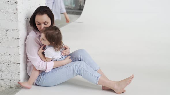 Beautiful Happy Family Sit on Floor and Cuddle in White Photo Studio