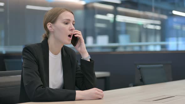 Angry Businesswoman Talking on Smartphone at Work