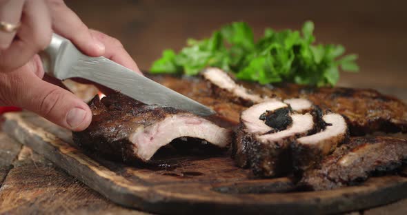 Men's Hands with a Knife Cut the Ribs of Grill To Pieces