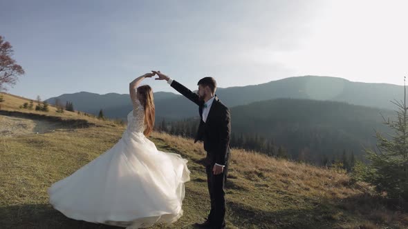 Newlyweds. Caucasian Groom with Bride Dancing on Mountain Slope. Wedding Couple