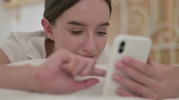 Close Up of Happy Young Woman Using Smartphone in Bed 