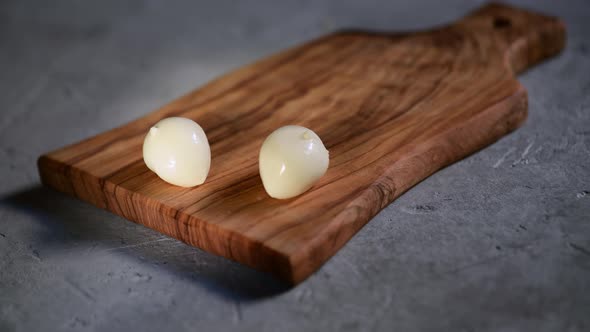 a hand puts the fresh small ball of mozzarella on a cutting board