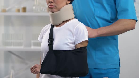 Doctor Applying Female Patient in Foam Cervical Collar Arm Sling, Treatment