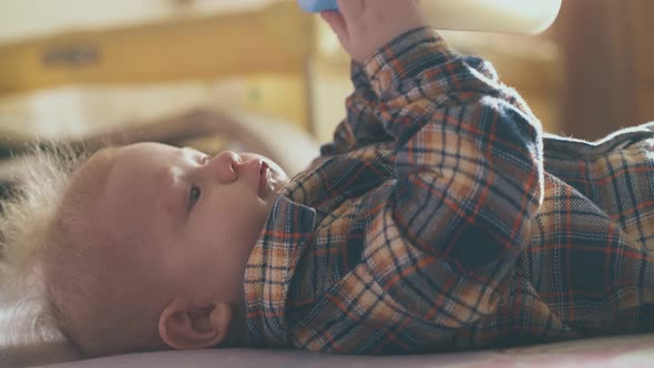 Little Baby Eats Tasty Milk Mix From Small Bottle on Bed