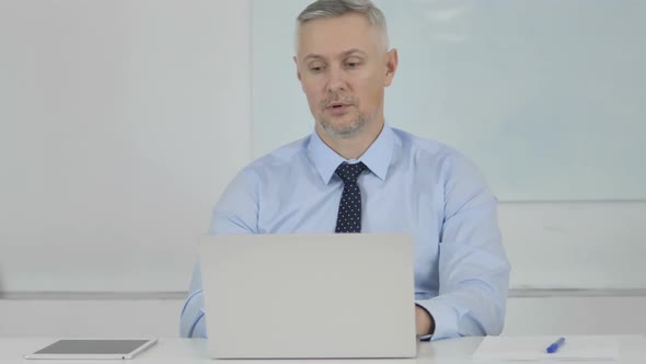 Tired Senior Businessman Yawning at Work