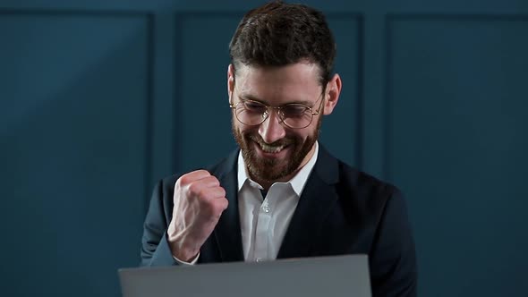 Businessman Works on a Laptop. He Succeeded Internationally By Winning Big contract.He`s Very Happy