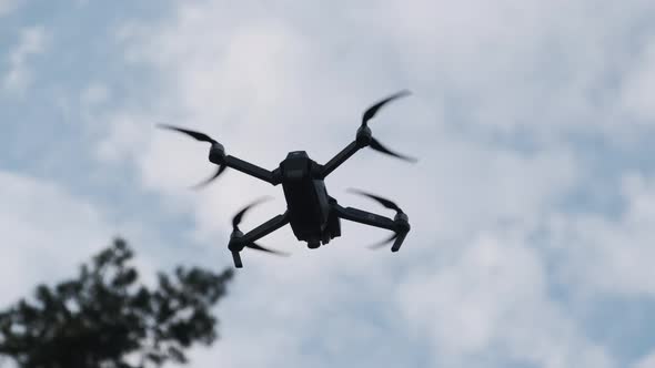 Drone Hangs in the Air Against the Blue Sky, View From Below. Slow Motion