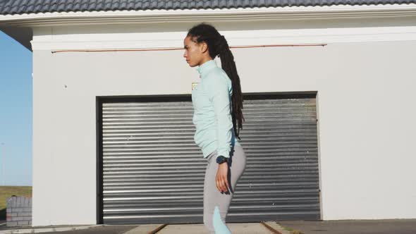 African american woman in sportswear stretching in street before exercising