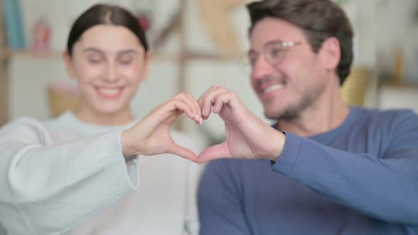 Portrait of Happy Hispanic Couple Holding Hands in Heart Shape