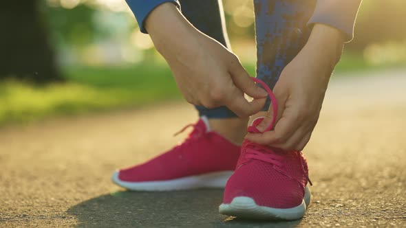 Woman Tying Shoelaces While Jogging or Walking at Sunset