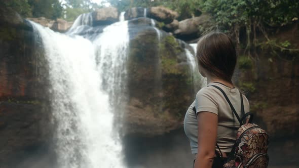 Rear View of Young Travel Woman Standing in Front of Waterfall